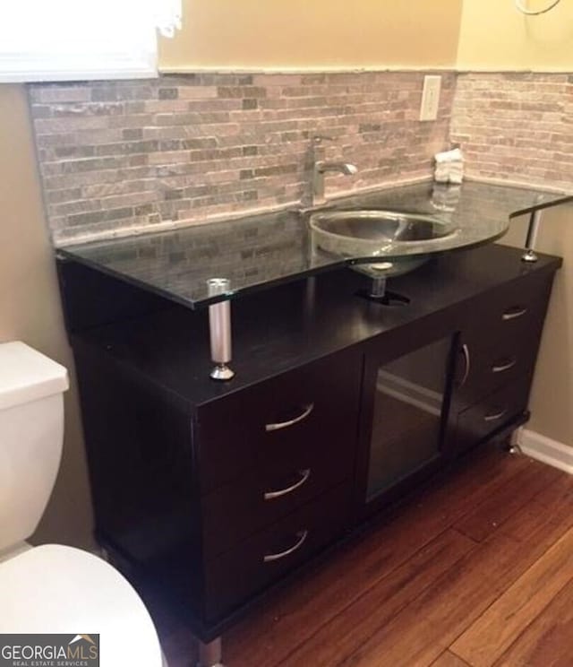 bathroom with toilet, decorative backsplash, hardwood / wood-style floors, and vanity