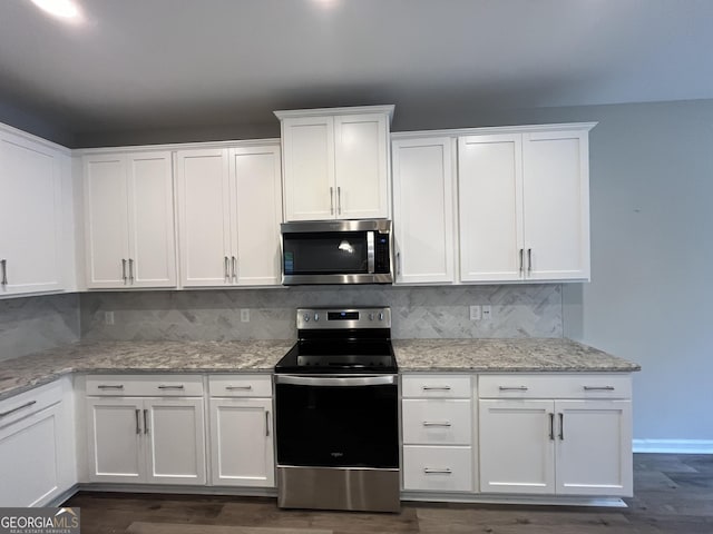 143 Madeira Dr, Brunswick, GA 31523 - kitchen with appliances with stainless steel finishes, white cabinetry, tasteful backsplash, dark wood finished floors, and light stone counters