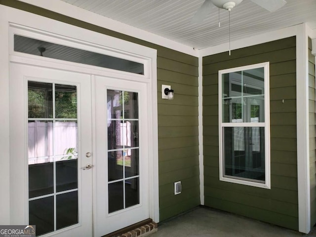 entryway featuring french doors, ceiling fan, concrete floors, and wood walls