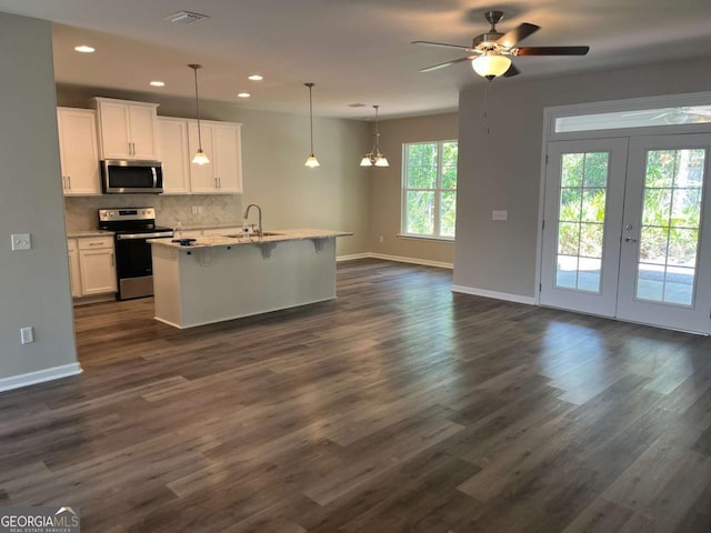 kitchen featuring white cabinets, appliances with stainless steel finishes, sink, backsplash, and a center island with sink