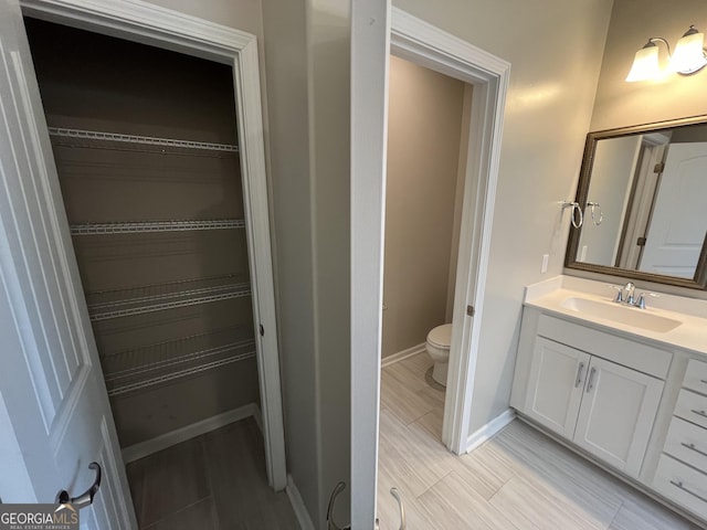 143 Madeira Dr, Brunswick, GA 31523 - bathroom with vanity, toilet, baseboards, wood finish floors, and a spacious closet