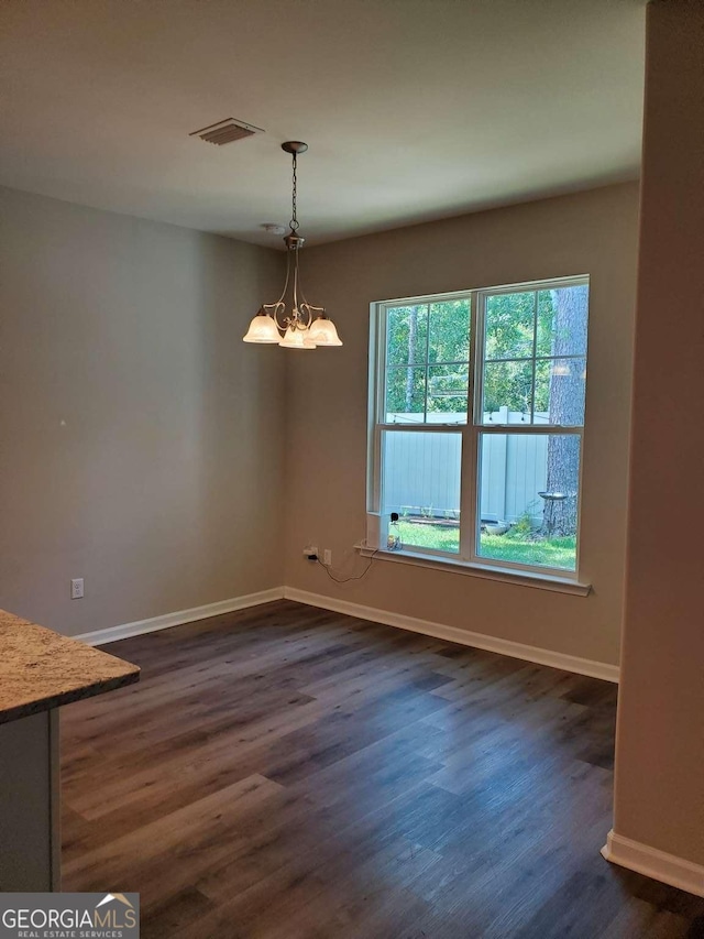 unfurnished dining area with dark hardwood / wood-style floors and a notable chandelier