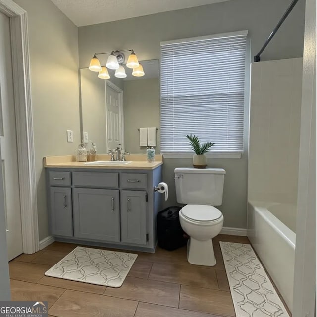 full bathroom with vanity, a textured ceiling, washtub / shower combination, and toilet