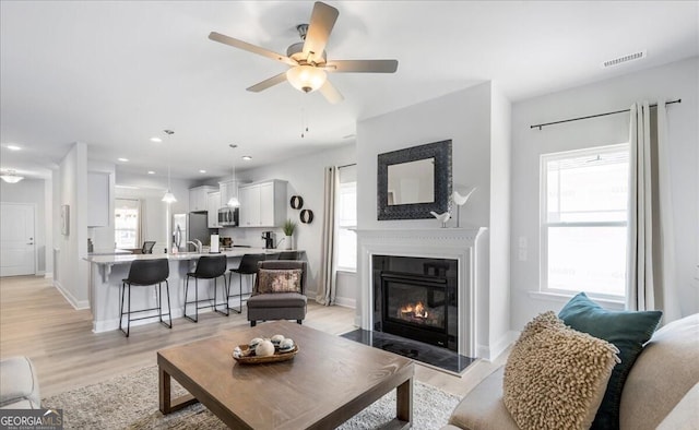 living room featuring ceiling fan and light wood-type flooring