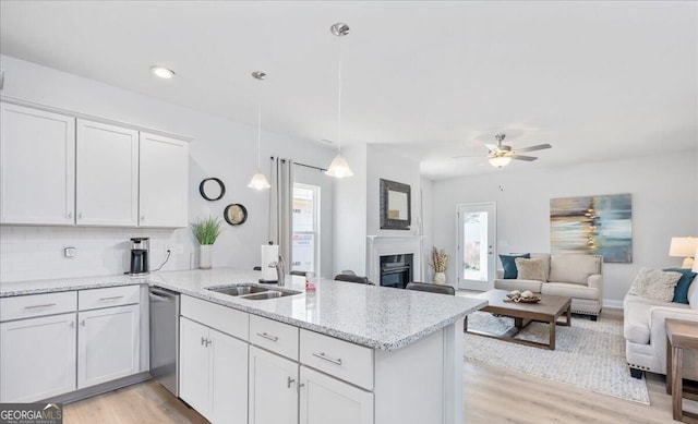 kitchen with tasteful backsplash, pendant lighting, kitchen peninsula, sink, and white cabinets