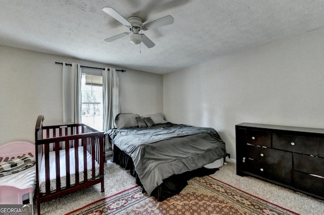 carpeted bedroom featuring a textured ceiling and ceiling fan