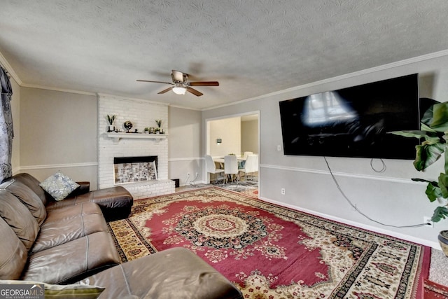 living room featuring crown molding, ceiling fan, a brick fireplace, and a textured ceiling