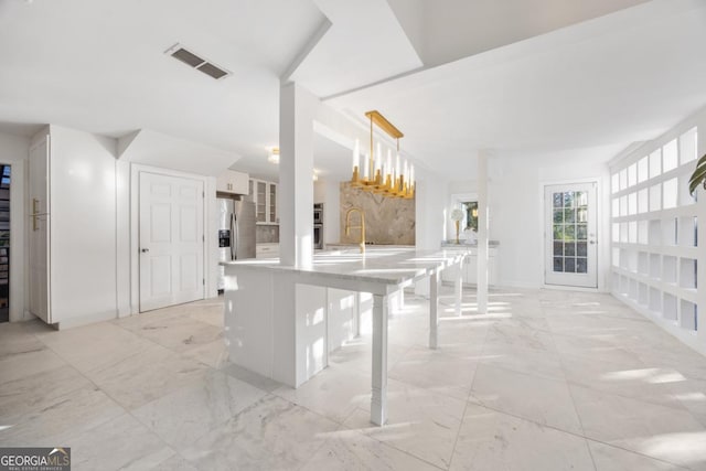 kitchen featuring decorative light fixtures, kitchen peninsula, stainless steel refrigerator with ice dispenser, sink, and a breakfast bar area