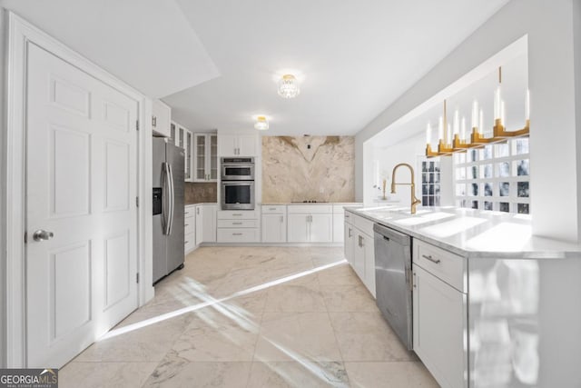 kitchen with appliances with stainless steel finishes, decorative backsplash, hanging light fixtures, white cabinets, and sink