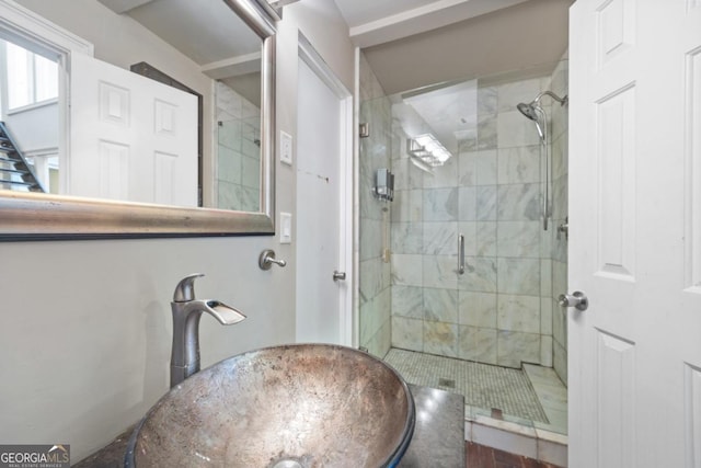 bathroom featuring a shower with shower door and sink