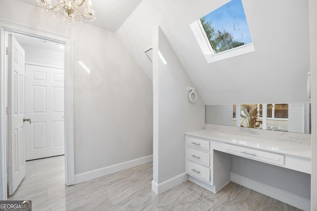 bathroom featuring vanity, lofted ceiling with skylight, and a notable chandelier