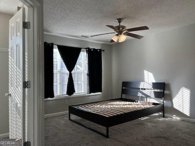 carpeted bedroom featuring ceiling fan and a textured ceiling