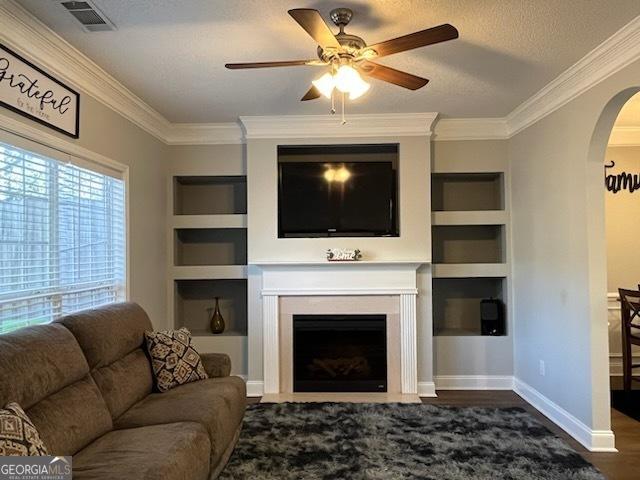 living room featuring crown molding, dark wood-type flooring, built in features, and a textured ceiling