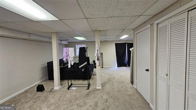 finished basement featuring carpet floors, a paneled ceiling, and baseboards