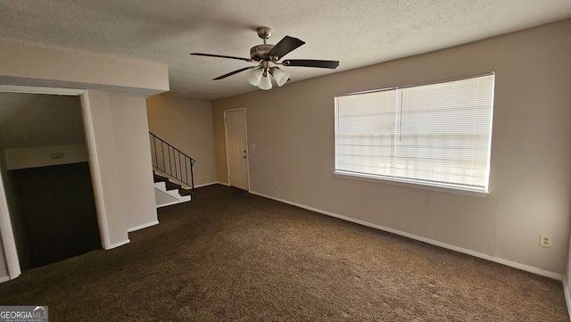 unfurnished living room featuring stairway, baseboards, dark carpet, and a textured ceiling