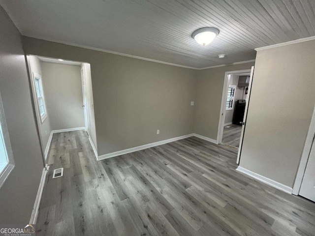 empty room featuring light wood-type flooring and crown molding