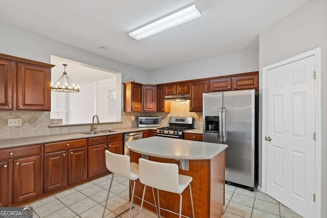 kitchen featuring a center island, sink, hanging light fixtures, appliances with stainless steel finishes, and a breakfast bar area