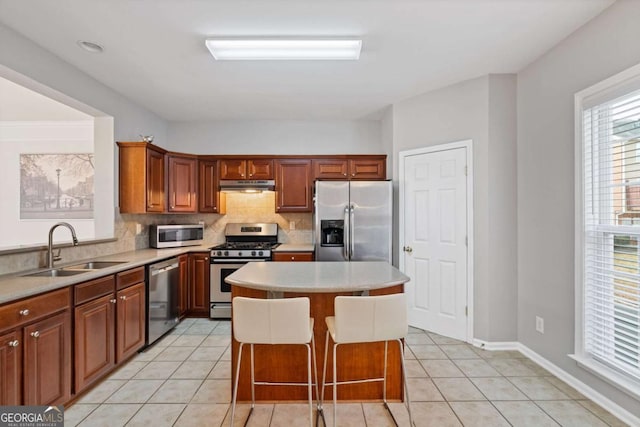 kitchen with light tile patterned flooring, appliances with stainless steel finishes, sink, and a kitchen island