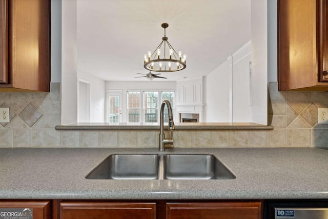 kitchen featuring ceiling fan with notable chandelier, sink, and decorative backsplash