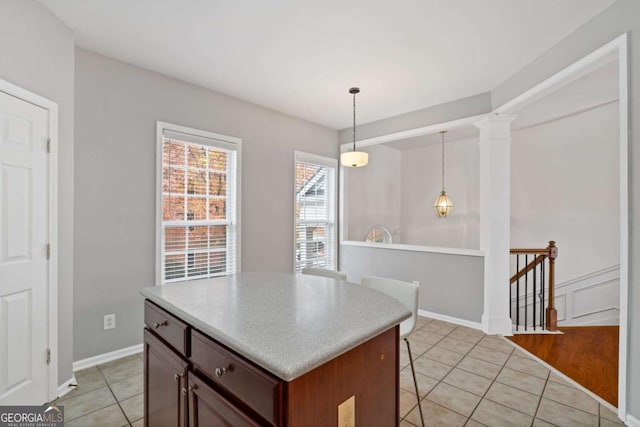 kitchen featuring decorative columns, light tile patterned floors, hanging light fixtures, and a kitchen island