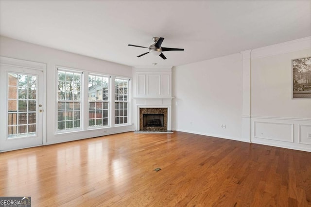 unfurnished living room featuring ceiling fan, a fireplace, and light hardwood / wood-style floors