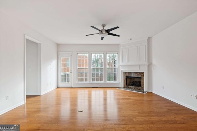 unfurnished living room featuring ceiling fan, light wood-type flooring, and a premium fireplace