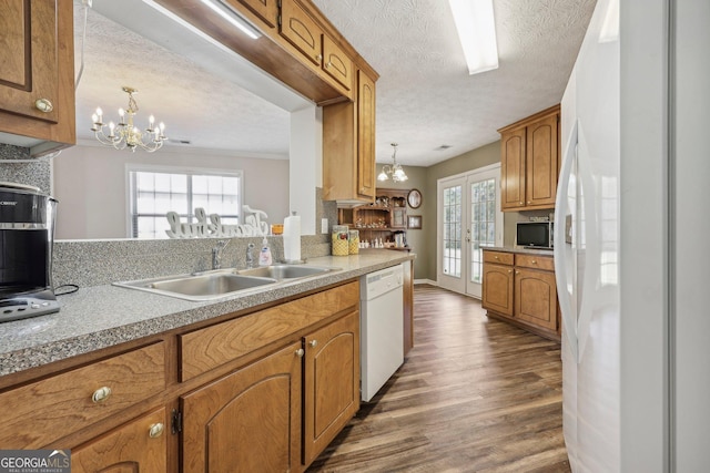 kitchen featuring white appliances, hanging light fixtures, and an inviting chandelier