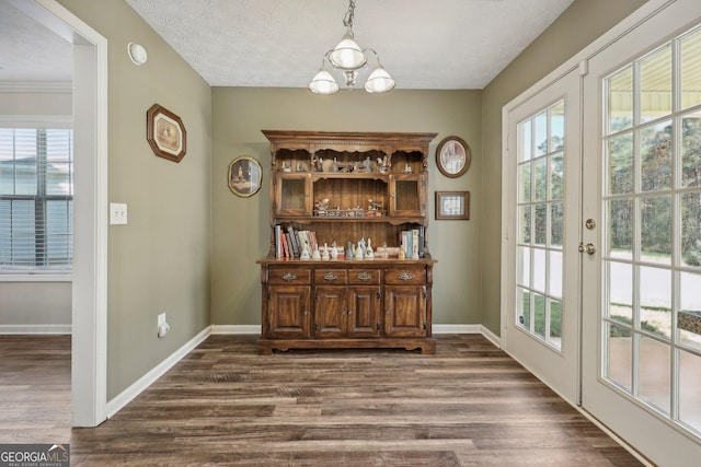 dining space with french doors, dark hardwood / wood-style floors, an inviting chandelier, and a textured ceiling