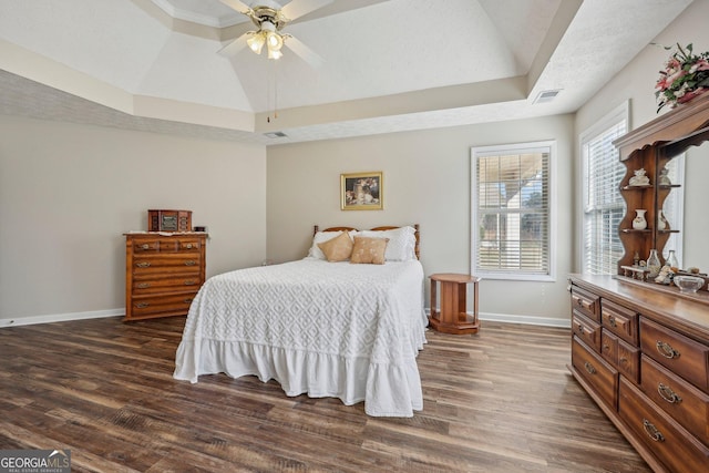 bedroom featuring ceiling fan, lofted ceiling, dark hardwood / wood-style floors, a tray ceiling, and a textured ceiling