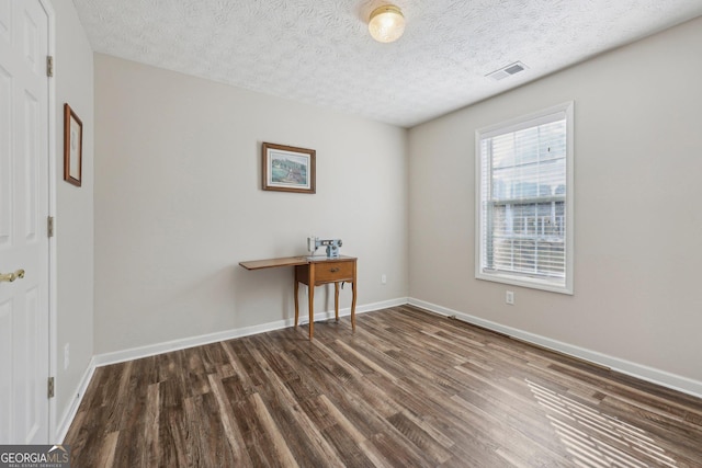 unfurnished room with dark wood-type flooring and a textured ceiling