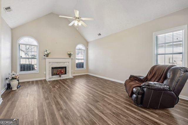 living room with ceiling fan, a high end fireplace, dark hardwood / wood-style flooring, and high vaulted ceiling