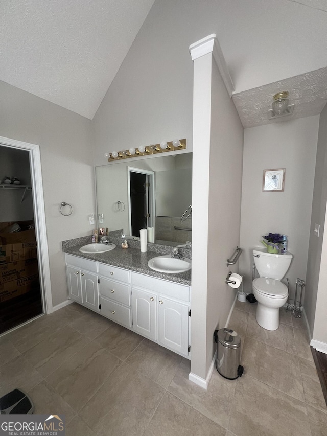 bathroom with toilet, tile patterned flooring, lofted ceiling, and vanity