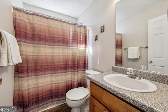 bathroom with a textured ceiling, walk in shower, vanity, and toilet