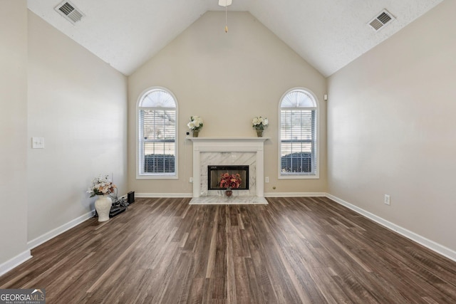 unfurnished living room featuring lofted ceiling, a high end fireplace, dark hardwood / wood-style floors, and plenty of natural light