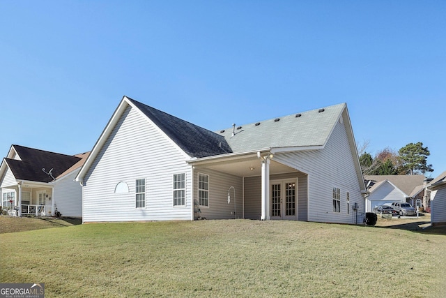 back of house with french doors and a lawn