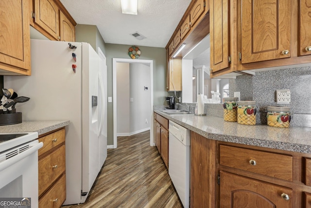 kitchen with tasteful backsplash, dark hardwood / wood-style floors, sink, white appliances, and a textured ceiling