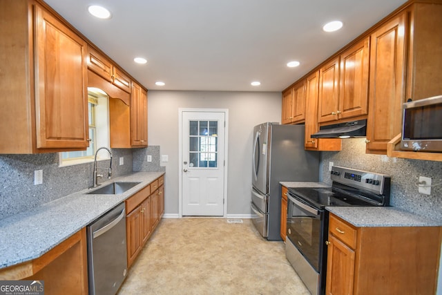 kitchen featuring light stone countertops, sink, a wealth of natural light, and appliances with stainless steel finishes