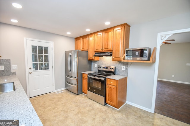 kitchen with tasteful backsplash, ceiling fan, sink, appliances with stainless steel finishes, and light stone countertops