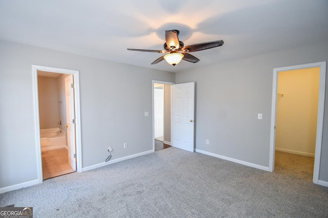 unfurnished bedroom with ceiling fan, carpet floors, connected bathroom, a walk in closet, and a closet