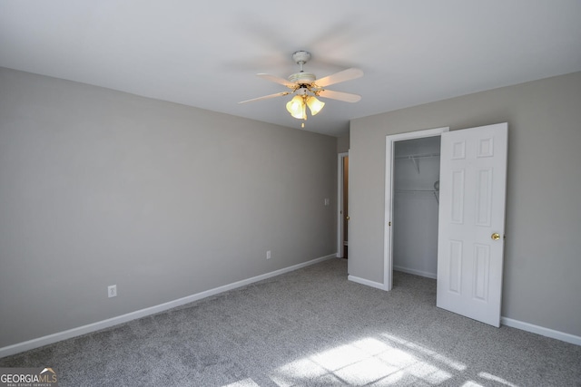 unfurnished bedroom featuring a spacious closet, ceiling fan, carpet flooring, and a closet