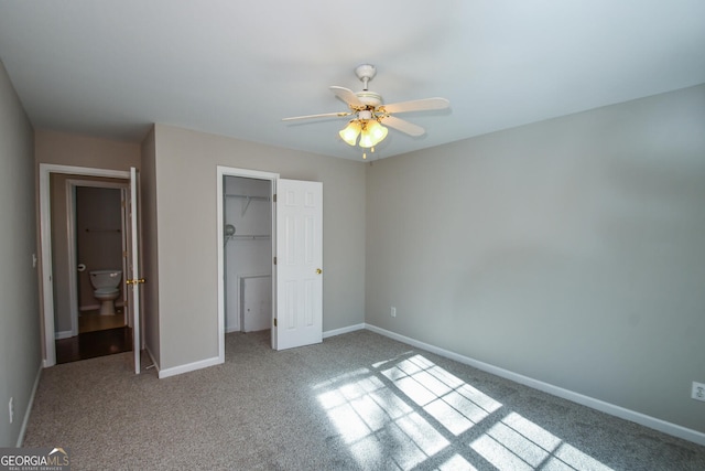 unfurnished bedroom with carpet, a walk in closet, a closet, ceiling fan, and ensuite bathroom