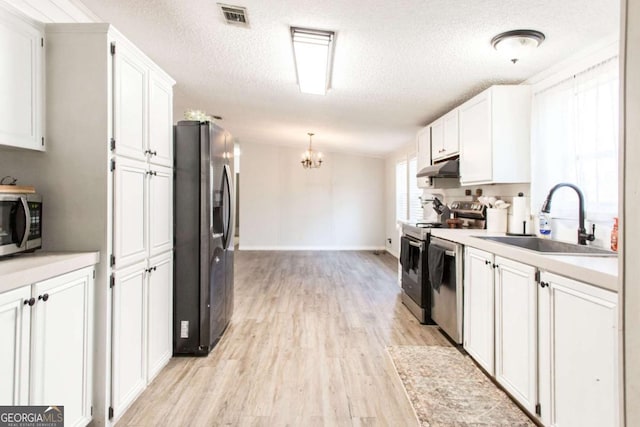 kitchen featuring a textured ceiling, white cabinets, stainless steel appliances, sink, and hanging light fixtures