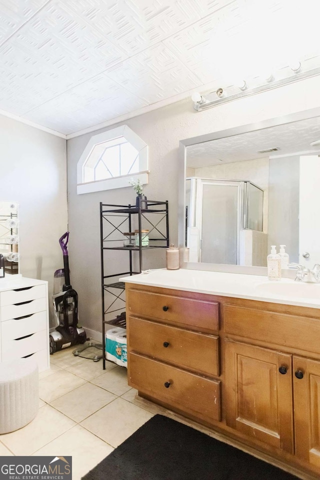 bathroom featuring tile patterned flooring, an enclosed shower, and vanity