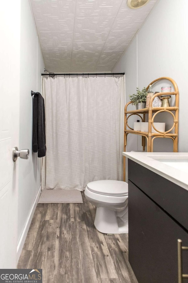 bathroom with hardwood / wood-style flooring, curtained shower, toilet, and vanity