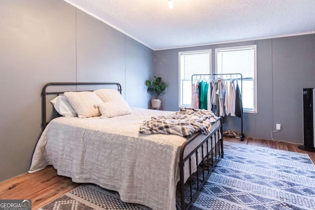 bedroom with a textured ceiling, dark hardwood / wood-style floors, and crown molding