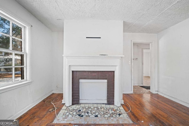 living room with a textured ceiling, a brick fireplace, and dark hardwood / wood-style flooring