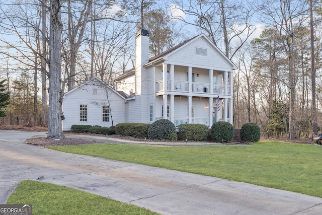 neoclassical / greek revival house with a front yard and a balcony