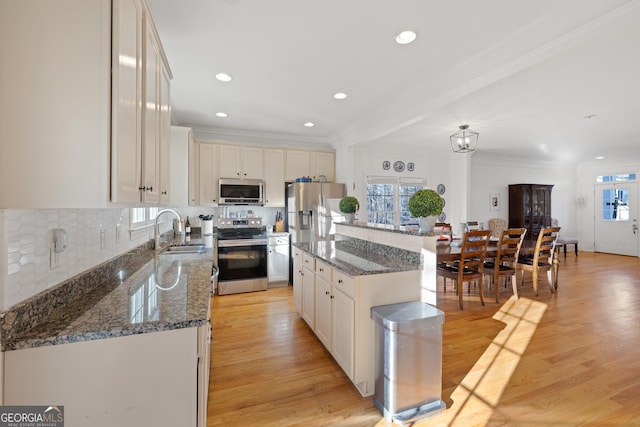 kitchen with white cabinets, appliances with stainless steel finishes, a kitchen island, tasteful backsplash, and sink