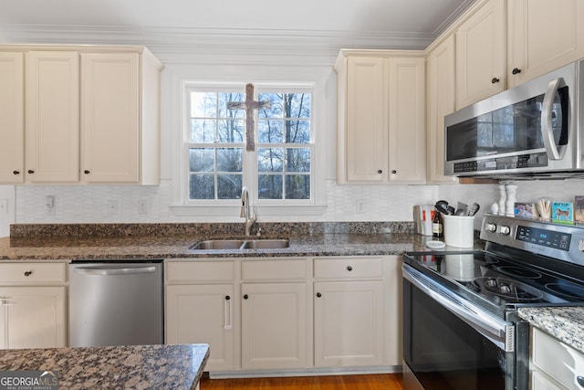 kitchen with backsplash, sink, appliances with stainless steel finishes, ornamental molding, and dark stone counters