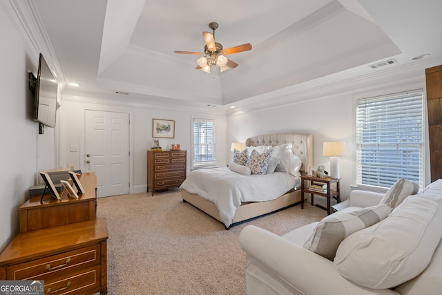 bedroom with ceiling fan, ornamental molding, light colored carpet, and a tray ceiling